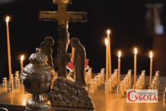 Запалені свічки та хрест у храмі
