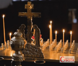 Запалені свічки та хрест у храмі