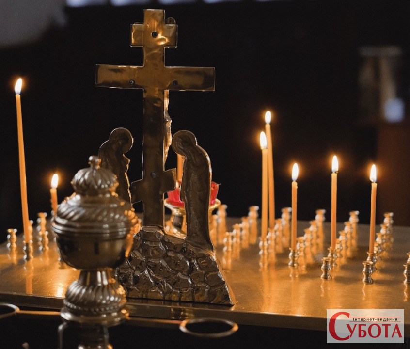 Запалені свічки та хрест у храмі