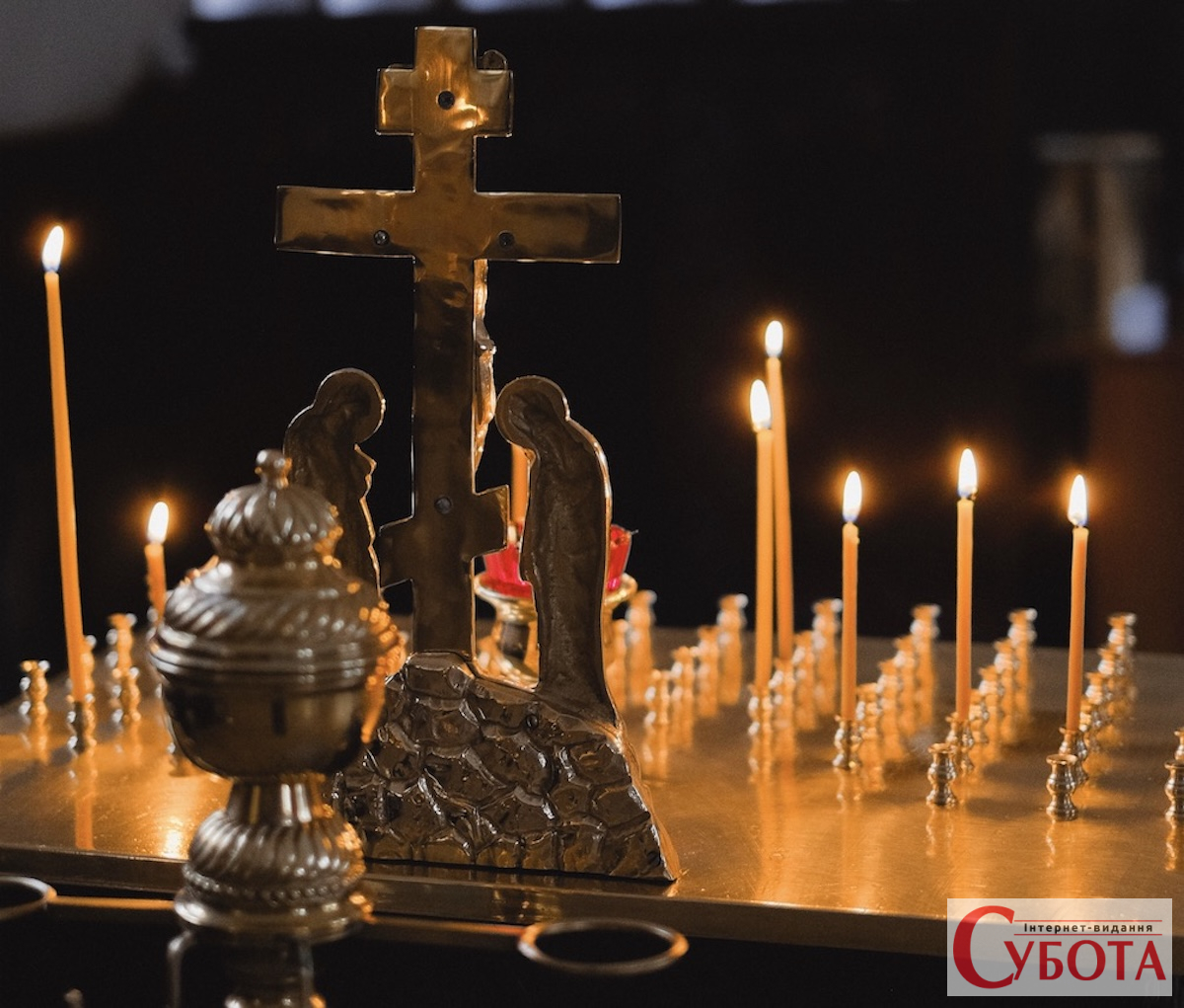 Запалені свічки та хрест у храмі