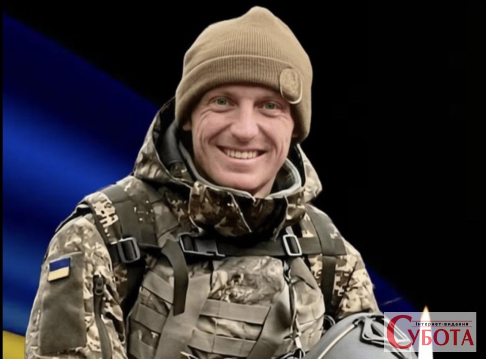 Портрет усміхненого українського захисника Олександра Максимчука на фоні прапора
