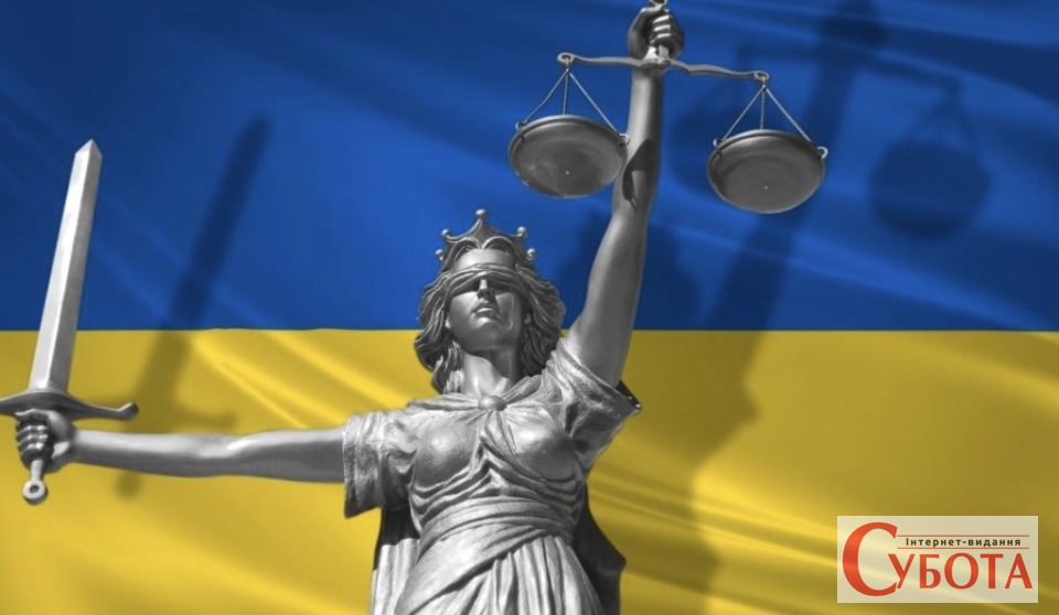 Статуя правосуддя Феміда на тлі прапора України під час суду за державну зраду на Житомирщині
