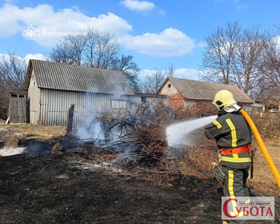 Рятувальник гасить палаючу суху траву та гілля біля будівель на Житомирщині