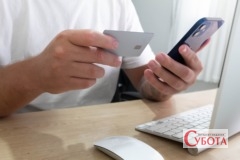 Руки людини з банківською карткою та смартфоном