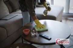 Cleaning a coffee table at home with cleaning supplies and worn furniture