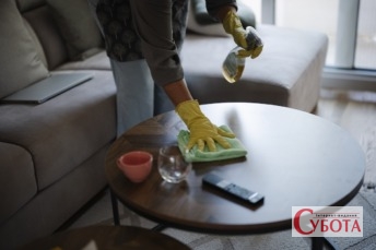 Cleaning a coffee table at home with cleaning supplies and worn furniture